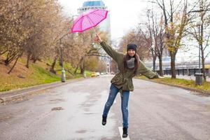 jovem andando com guarda-chuva em dia chuvoso de outono foto