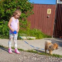 menina andando com seu cachorro na coleira foto