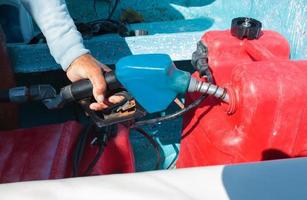 homem abastecendo o barco a motor antes da viagem foto