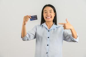 retrato de uma jovem asiática positiva mostrando o salário de bom humor do cartão de crédito isolado no fundo branco foto