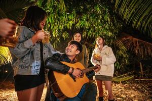 retrato de grupo asiático feliz de amigos se divertindo com música jantando e bebendo juntos ao ar livre - grupo de amigos felizes brindando cervejas - pessoas, comida, estilo de vida de bebida, conceito de celebração de ano novo. foto