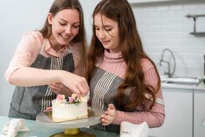 mãe e filha preparando e decorando bolo caseiro foto