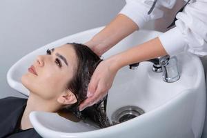 cabeleireiro profissional lavando o cabelo de jovem no salão de beleza. close-up do cabelo da mulher no salão de beleza, conceito de penteado foto