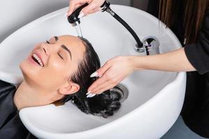 cabeleireiro profissional lavando o cabelo de jovem no salão de beleza... close-up do cabelo da mulher no salão de beleza, conceito de penteado foto