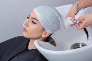 cabeleireiro profissional lavando o cabelo de jovem no salão de beleza. close-up do cabelo da mulher no salão de beleza, conceito de penteado foto