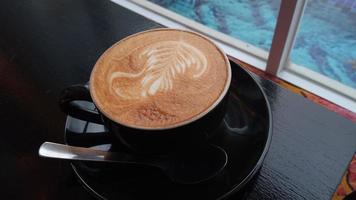 close-up de arte capuchino em uma xícara de café preto foto