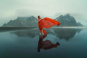 mulher sensual em roupas vermelhas na praia de reynisfjara fotografia cênica foto