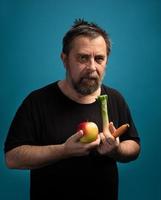homem em uma camiseta preta segura frutas e legumes foto
