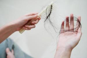 mulher asiática tem problema com perda de cabelo comprido anexado na mão.