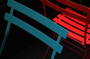cadeiras de metal azuis e vermelhas em fundo preto foto