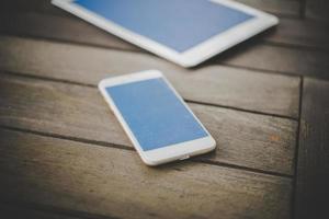 smartphone e tablet em uma mesa de madeira foto