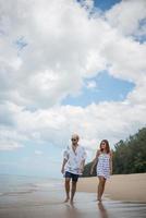 jovem casal feliz caminhando na praia foto