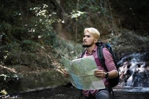 aventureiro observando mapa em um caminho de montanha foto