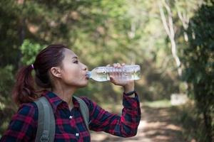 turista mulher feliz com mochila bebendo água na natureza foto