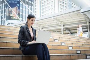 mulher de negócios usando laptop senta-se na escada. conceito de pessoas de negócios. foto