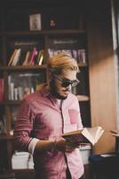 jovem hippie barbudo lendo um livro em um café foto