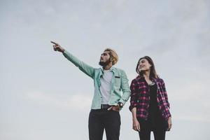 casal apaixonado de hipster em pé contra o céu claro foto