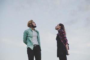 casal apaixonado de hipster em pé contra o céu claro foto