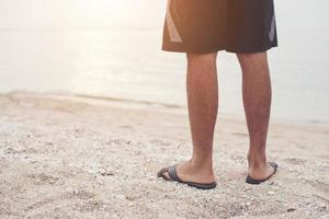 pernas de jovem em sandálias na praia