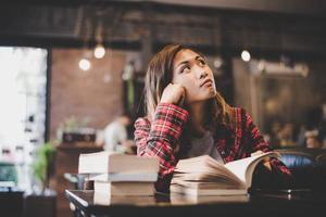 hipster mulher adolescente sentado desfrutar de ler um livro no café. foto