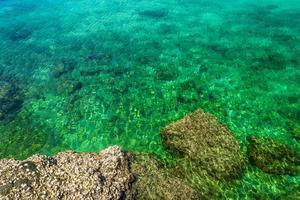 Ilha de rocha tropical na praia com águas cristalinas verde-azuladas foto