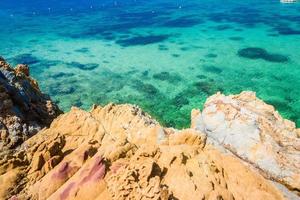 Ilha de rocha tropical na praia com águas cristalinas verde-azuladas foto