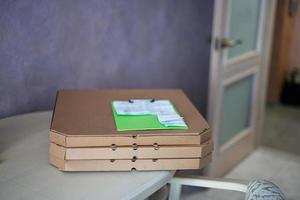 caixas de pizza de papelão com prancheta de entrega na cozinha na mesa. foto