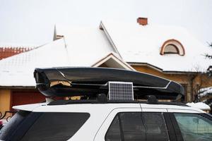 painel solar portátil perto do rack de teto do carro suv no inverno. foto