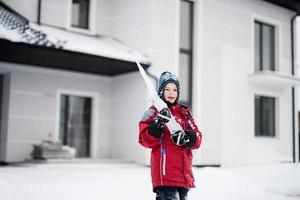 menino com grande sincelo de gelo no inverno contra a casa. foto