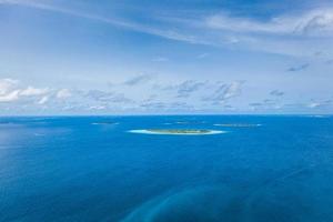 ilhas tropicais e atóis nas maldivas de vista aérea. famoso destino de viagem e férias de luxo ou conceito de férias de verão. paisagem aérea do mar azul e resorts, hotéis. natureza bela foto