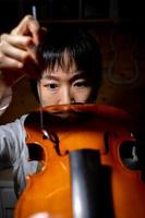 jovem fabricante de violino chinês verificando a qualidade de seu violino foto