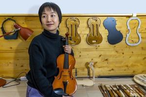 jovem fabricante de violino chinês trabalhando em sua oficina foto