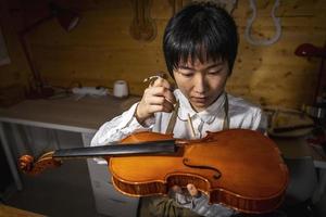 jovem fabricante de violino chinês trabalhando em sua oficina foto