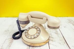 telefone vintage colorido marfim sobre uma mesa de madeira branca foto