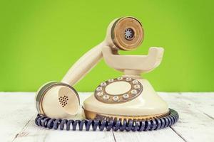 telefone vintage colorido marfim sobre uma mesa de madeira branca foto