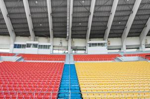 assentos laranja e amarelos vazios no estádio, fileiras de assentos em um estádio de futebol foto