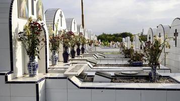 o cemitério público contém sepulturas idênticas de cerâmica branca com flores. foto
