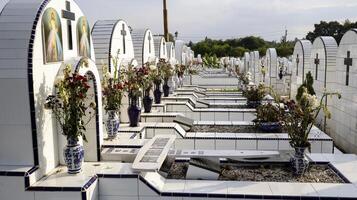 o cemitério público contém sepulturas idênticas de cerâmica branca com flores. foto