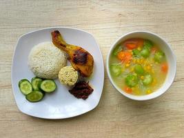 comida saudável. um prato de arroz branco com frango grelhado e uma tigela de sopa na mesa, vista de cima foto