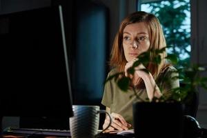 mulher trabalha em home office remotamente, usando computador foto