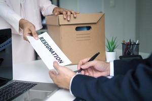 os jovens funcionários com as coisas na caixa de papel e enviar uma carta de demissão à gerência. idéias de mudança de emprego renunciar ao emprego foto