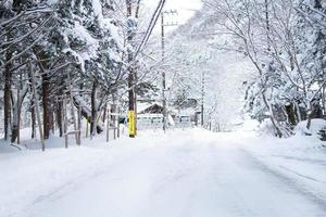 nikko, japão - 26 de janeiro de 2023. lâmpada de tungstênio e uma placa de vila japonesa, estrada coberta de neve pesada em heike no sato village na prefeitura de tochigi, cidade de nikko, foto