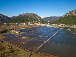 vista aérea do drone da salina na cidade de ston, na croácia. muralhas fortificadas nas colinas ao fundo. campos de sal. obras de sal de pedra. turismo perto do mar adriático. visitas históricas. foto