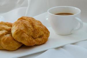 croissant de manteiga e uma xícara de café no café da manhã foto