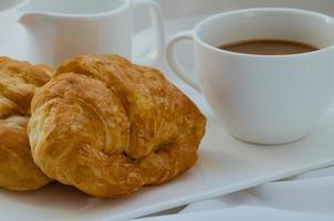 croissant de manteiga e uma xícara de café no café da manhã foto