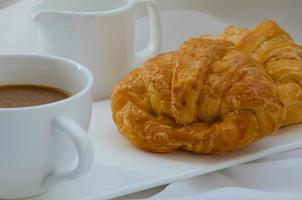 croissant de manteiga e uma xícara de café no café da manhã foto