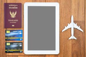 passaporte de vista superior com cartão de crédito e tablet digital simulado na mesa de madeira foto