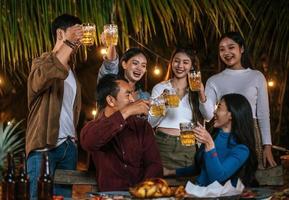 retrato de amigos asiáticos felizes jantando juntos - jovens brindando copos de cerveja jantar ao ar livre - pessoas, comida, estilo de vida de bebida, conceito de celebração de ano novo. foto