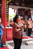 bandung, indonésia, 2020 - o visitante rezando junto com os monges em frente às oferendas ao deus foto