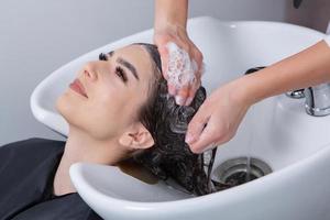 cabeleireiro profissional lavando o cabelo de jovem no salão de beleza. close-up do cabelo da mulher no salão de beleza, conceito de penteado foto